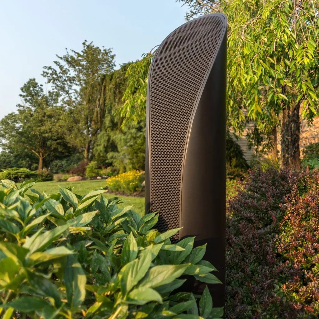 A tall Coastal Source line-source bollard speaker standing in a planted border