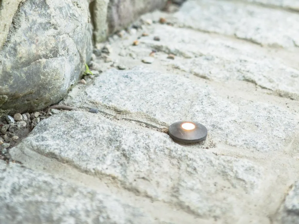 A small Coastal Source in-grade light set flush in a stone paver