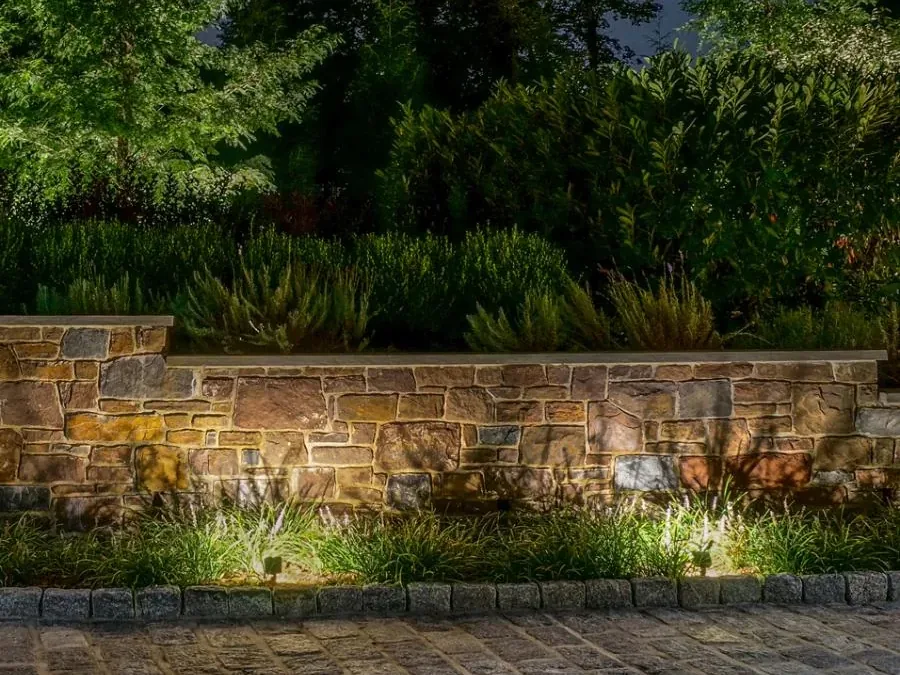 A stone garden wall washed in warm light at dusk
