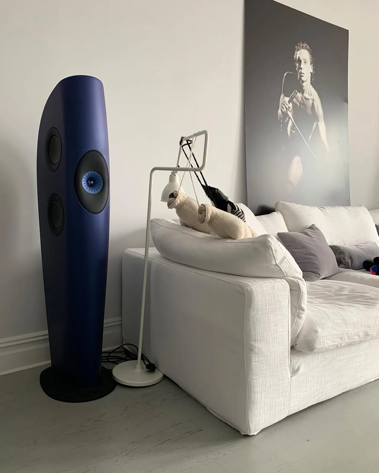 A blue KEF floorstanding speaker beside a white sofa