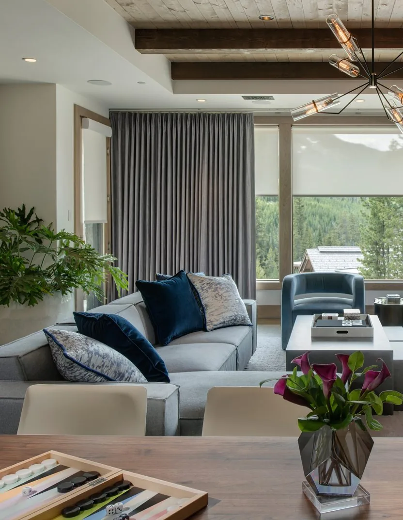 A family room with Lutron roller shades and drapery on a wall of glass