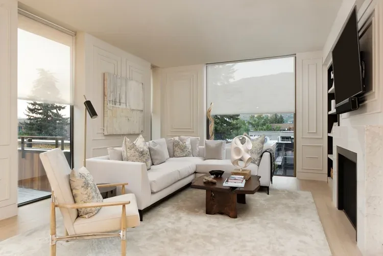 A living room where Savant shades filter daylight across a wall of windows