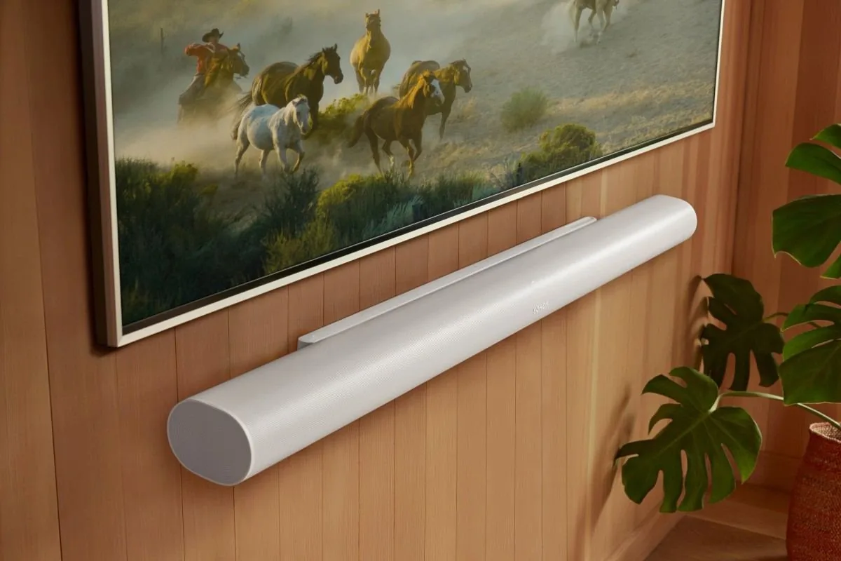 A white Sonos Arc Ultra mounted on a wood wall beneath a television