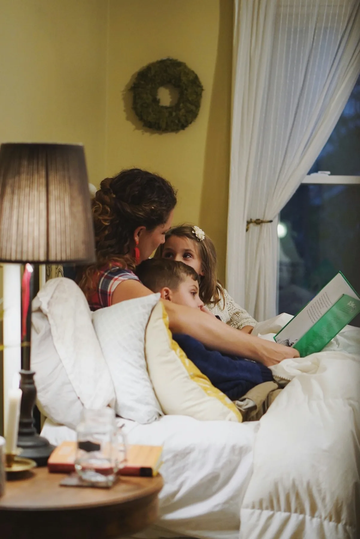 A parent reading with two children on a sofa with a tablet